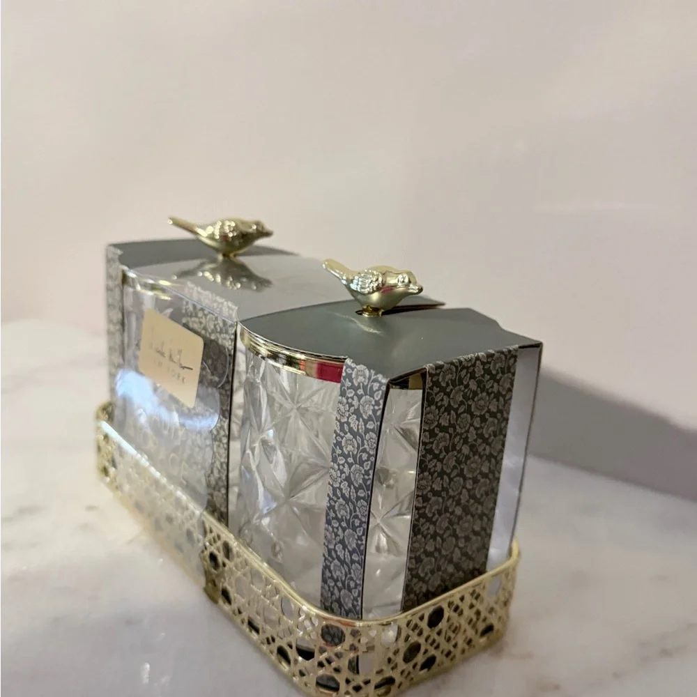 two-piece glass storage jar set with a gold bird lid and decorative tray.